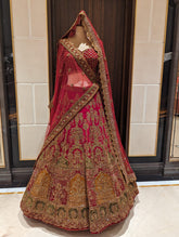 Traditional embroidered lehenga with red and gold patterns on a mannequin against a tiled wall.