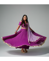 Woman in a purple lehenga with a flowing skirt on a gray background