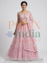 Woman wearing a pink lehenga on a light gray background.