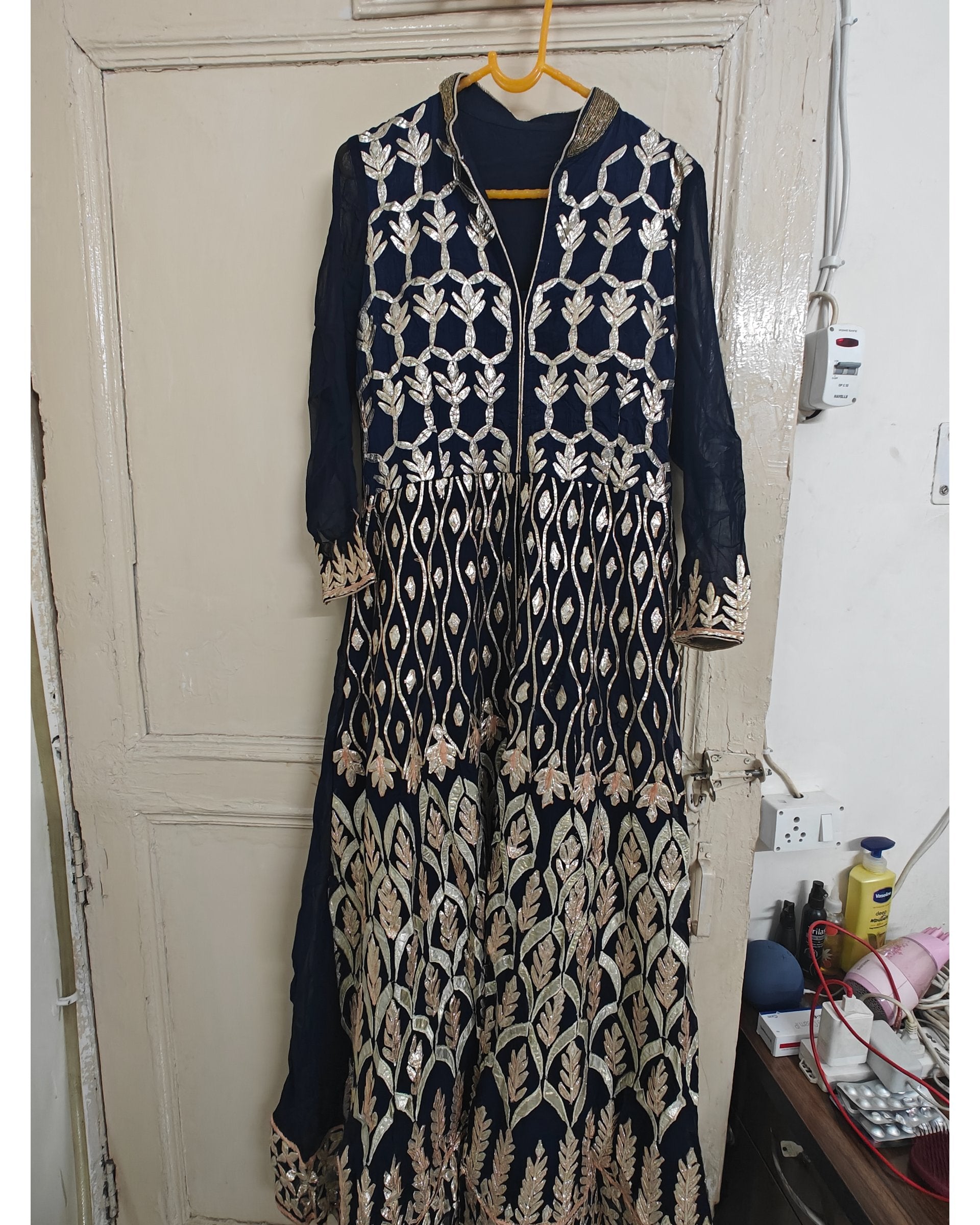 Navy blue and beige embroidered kurta hanging on a door