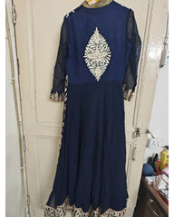 Navy blue traditional outfit with intricate white embroidery on a beige door.