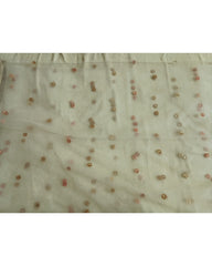 A close-up of a sheer off-white fabric with scattered small metallic gold and pink sequins or beads arranged in vertical dotted lines.