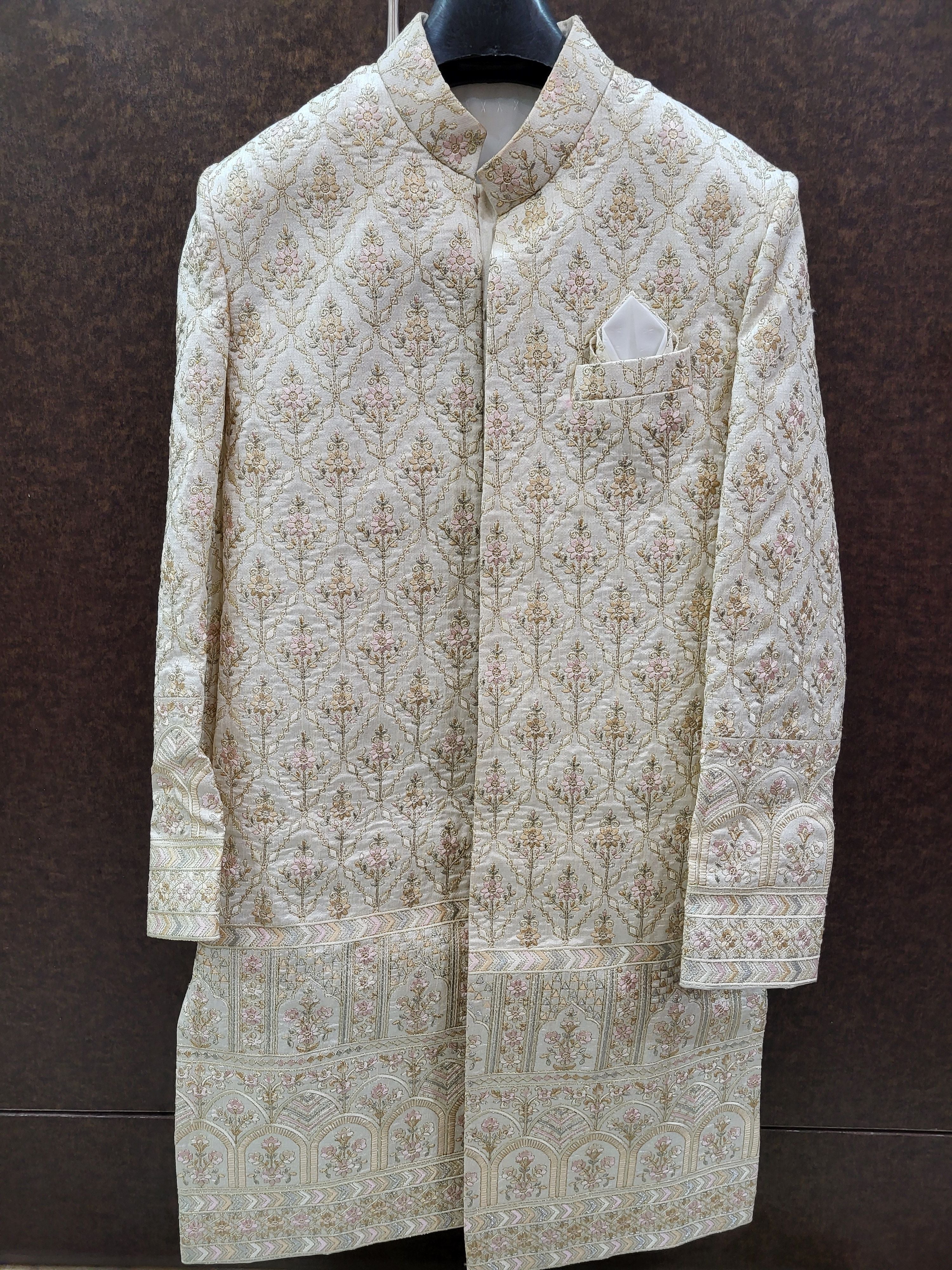 Traditional embroidered sherwani on a hanger against a dark background