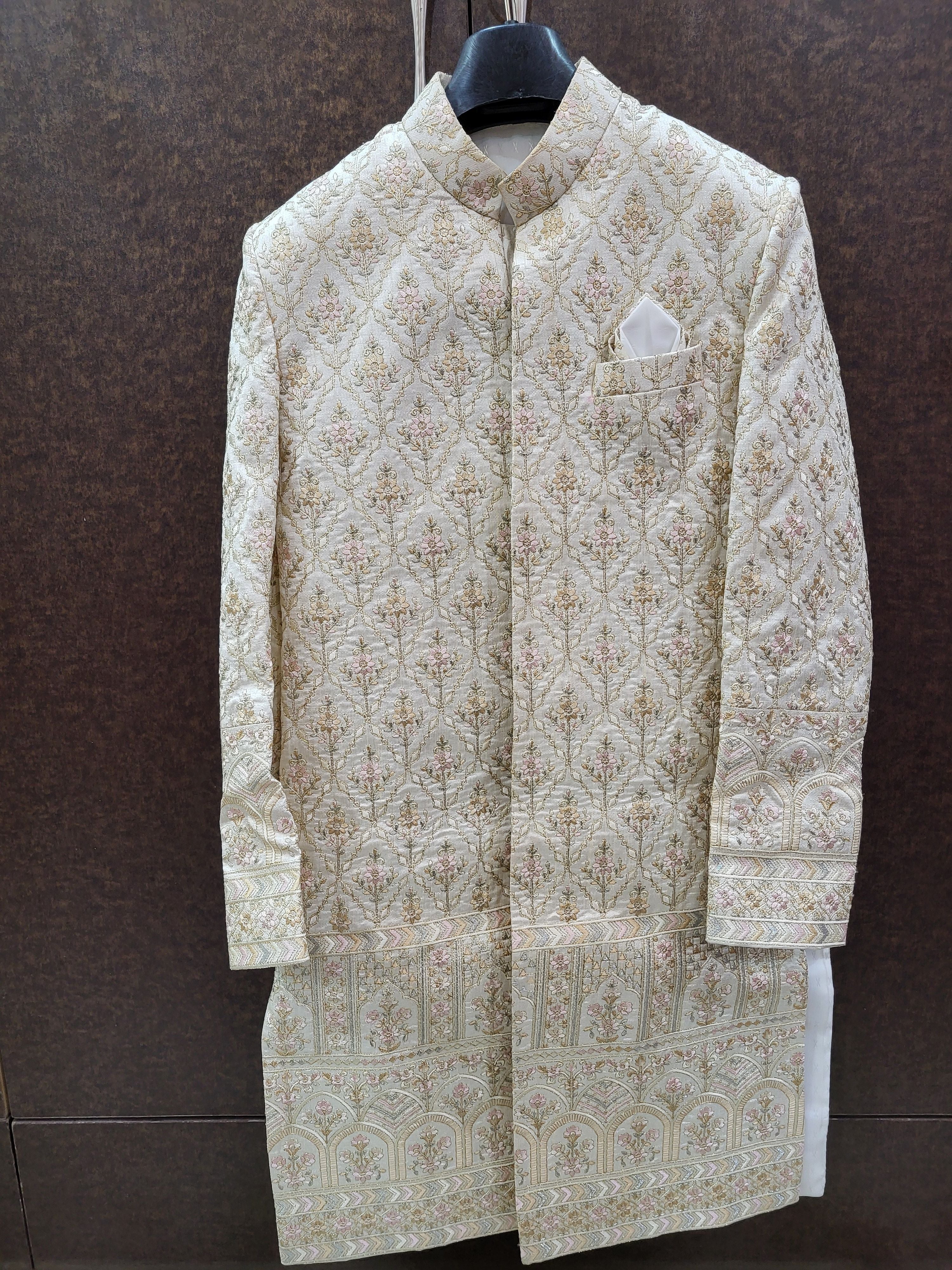 Traditional embroidered sherwani on a hanger against a brown background