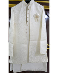 An off-white/cream traditional men's outfit consisting of a long-sleeved embroidered jacket and a matching kurta, displayed on a hanger against a dark wooden door background.