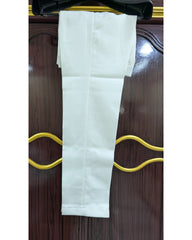 A pair of white trousers folded and hanging on a black hanger against a dark brown wooden door with gold-colored handles.