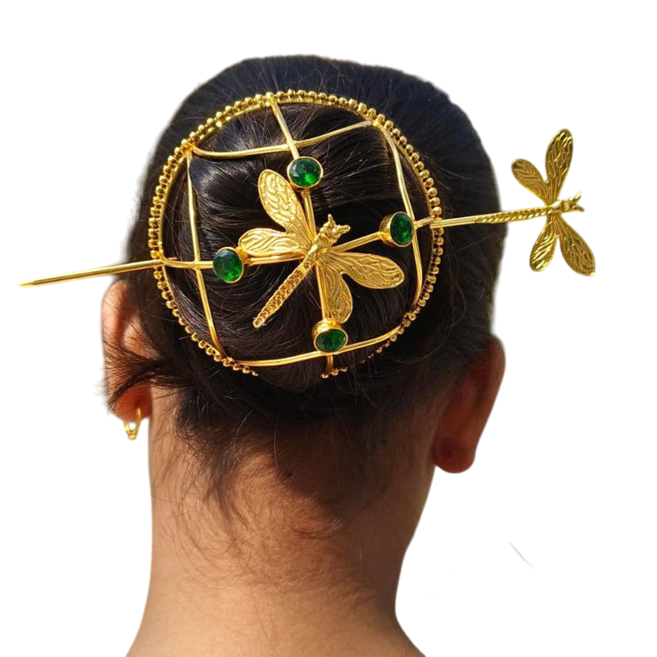 Gold hair accessory with dragonfly design on a person's head against a white background