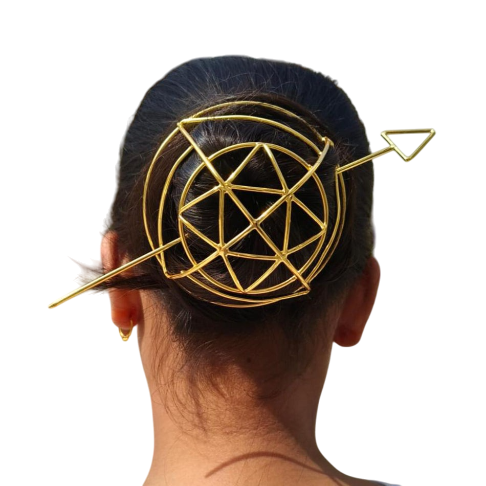 Gold geometric hair clip on a person's head against a white background