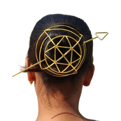 Gold geometric hair clip on a person's head against a white background