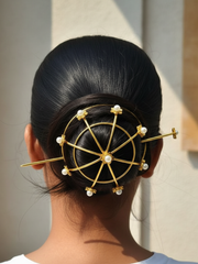 Person with a stylish hair bun adorned with gold and pearl hair accessories.