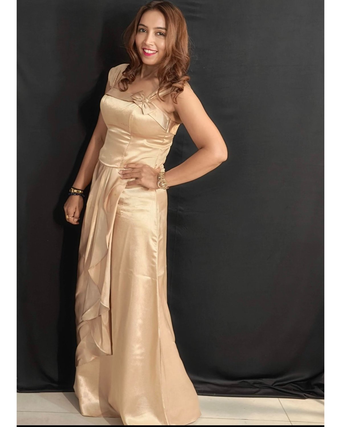 Woman wearing a beige evening gown against a black background