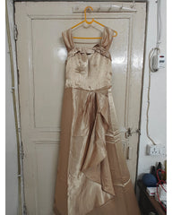 Beige satin dress hanging on a yellow hanger against a white door.