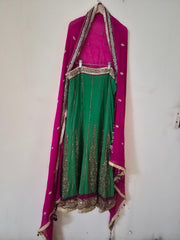 Traditional pink and green embroidered outfit on a white wall
