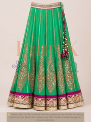 Green embroidered lehenga with gold embroidery details on a beige background