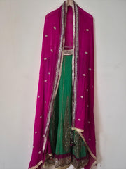 Traditional Indian outfit with pink dupatta and green lehenga on a white background