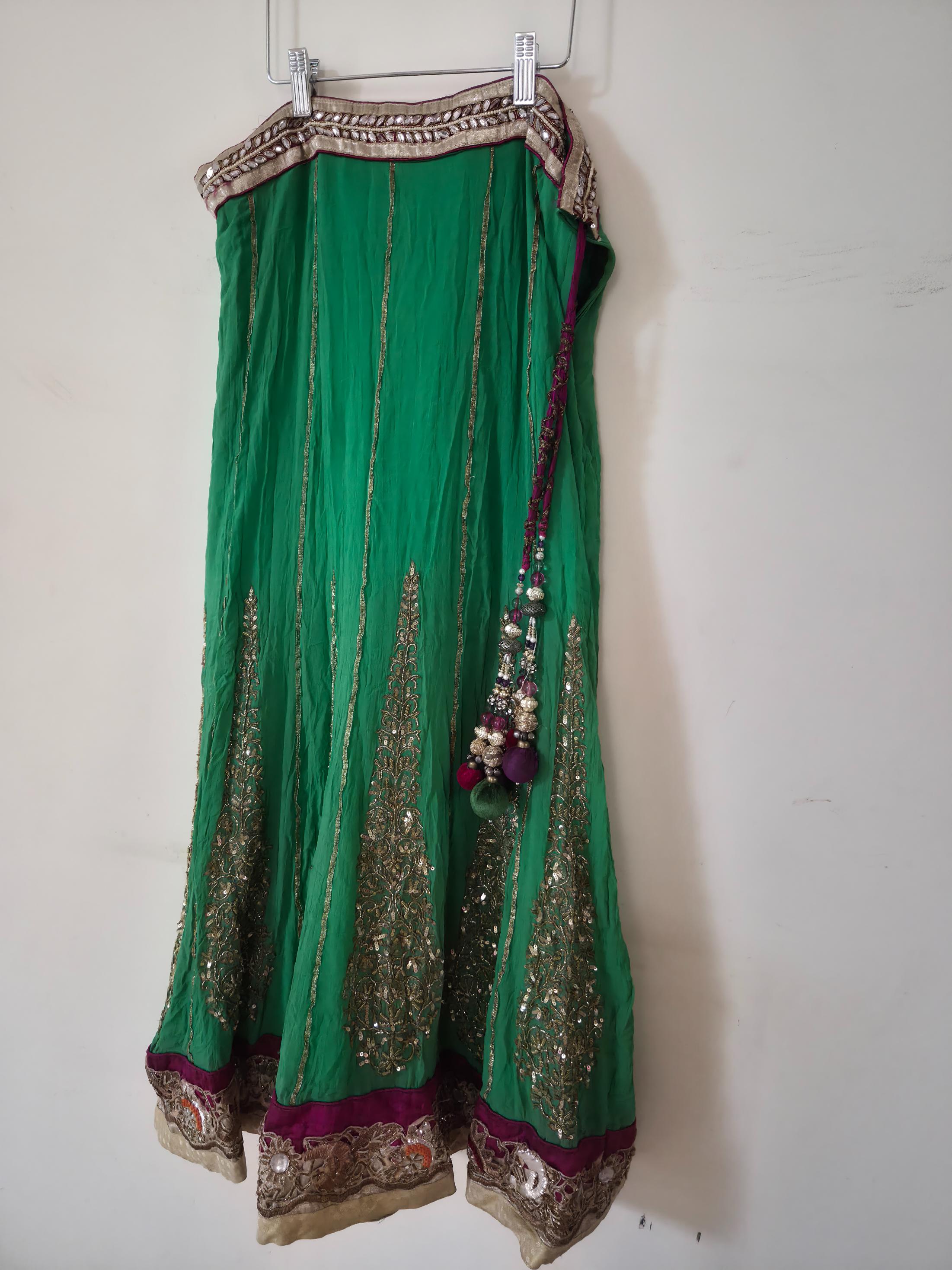 Green traditional lehenga with gold embroidery on a white background