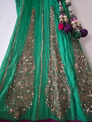 Green embroidered fabric with intricate patterns and decorative elements on a white background
