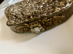 Gold glittery clutch bag with intricate designs on a white surface