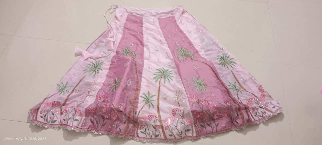 Pink lehenga skirt with floral patterns on a plain background
