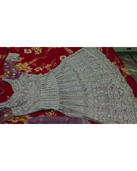 A light lavender-gray embroidered dress or kurta laid flat on a red floral fabric surface.