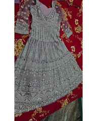 A heavily embellished lavender and silver embroidered dress laid flat on a red floral fabric background.