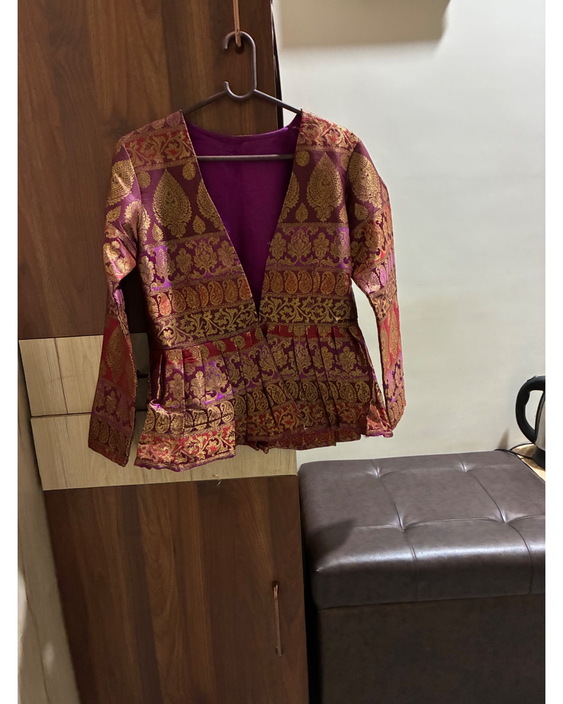 Patterned jacket on a hanger against a neutral wall.