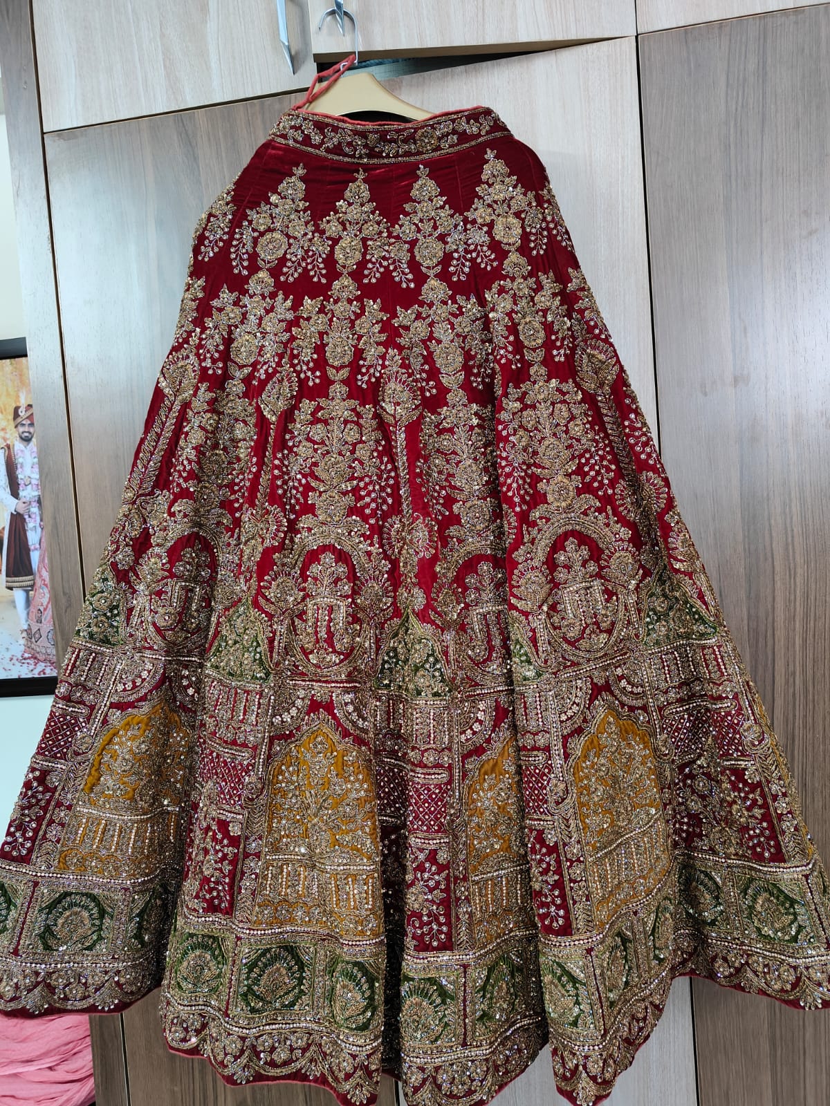 Indian traditional lehenga skirt with intricate gold embroidered patterns on a hanger