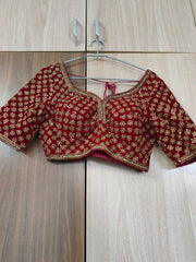 Red embroidered blouse on a hanger against a wooden floor background