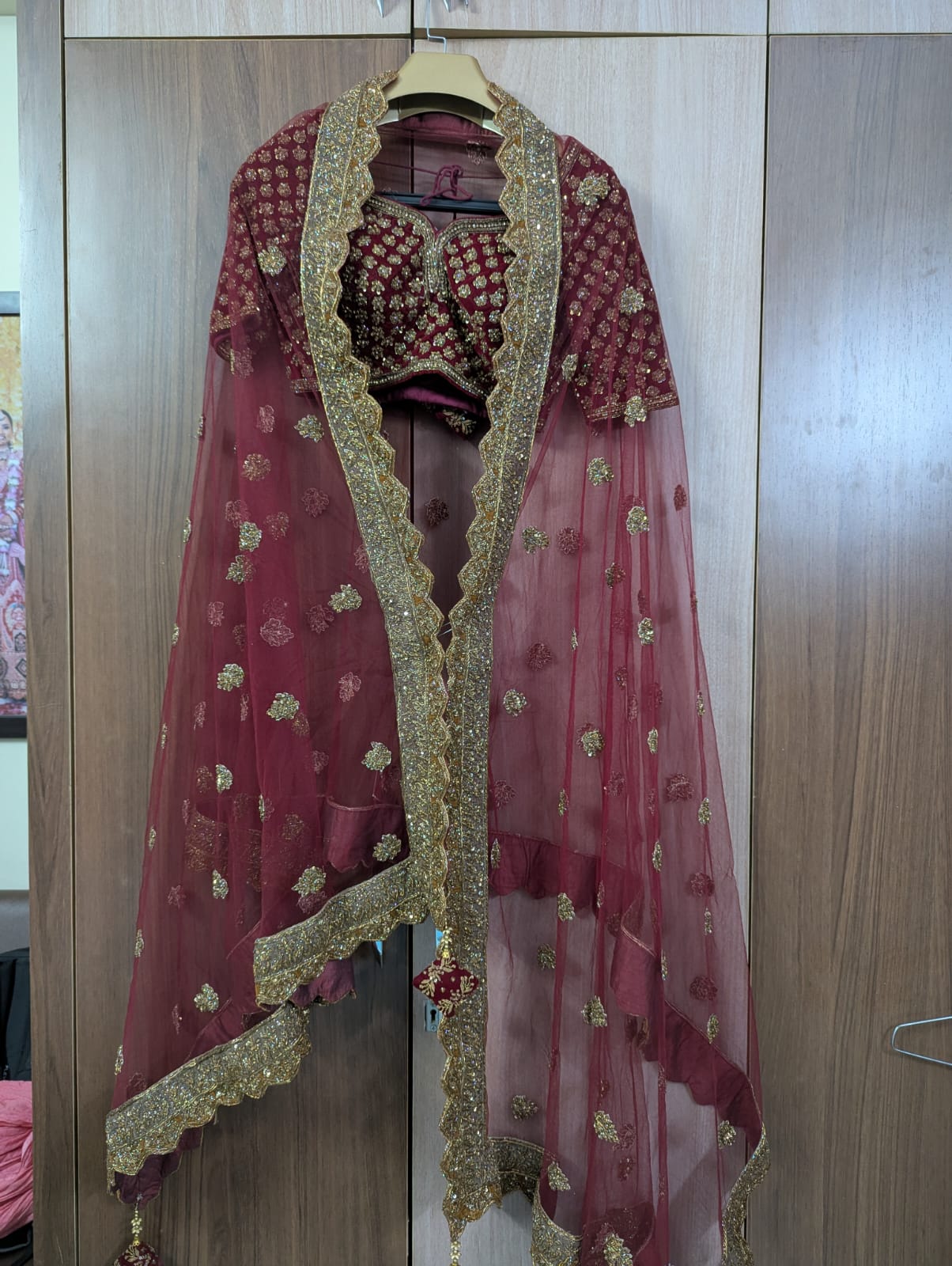 Maroon embroidered choli with a dupatta on a wooden door