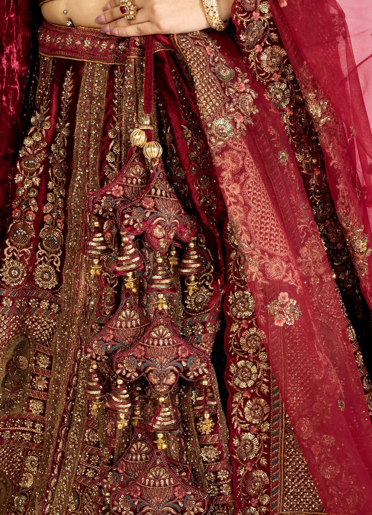 Close-up of a red and gold embroidered bridal lehenga skirt with intricate patterns.