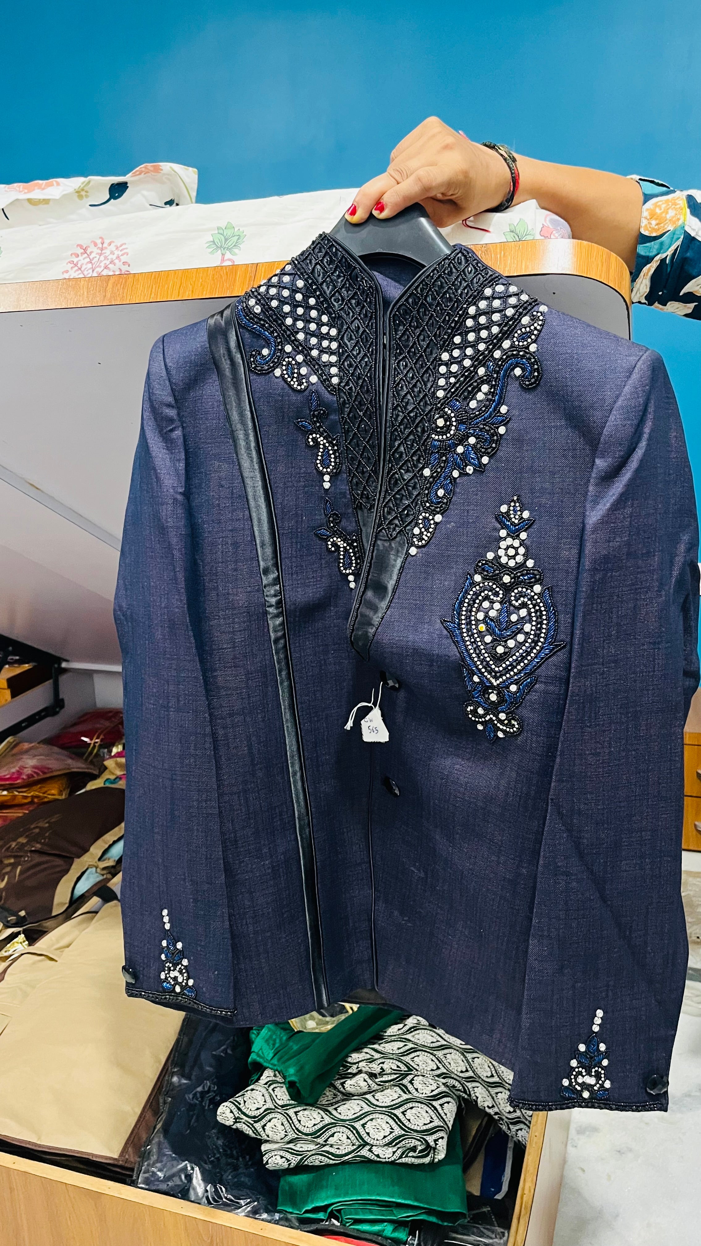 Blue embroidered jacket against a blue wall.