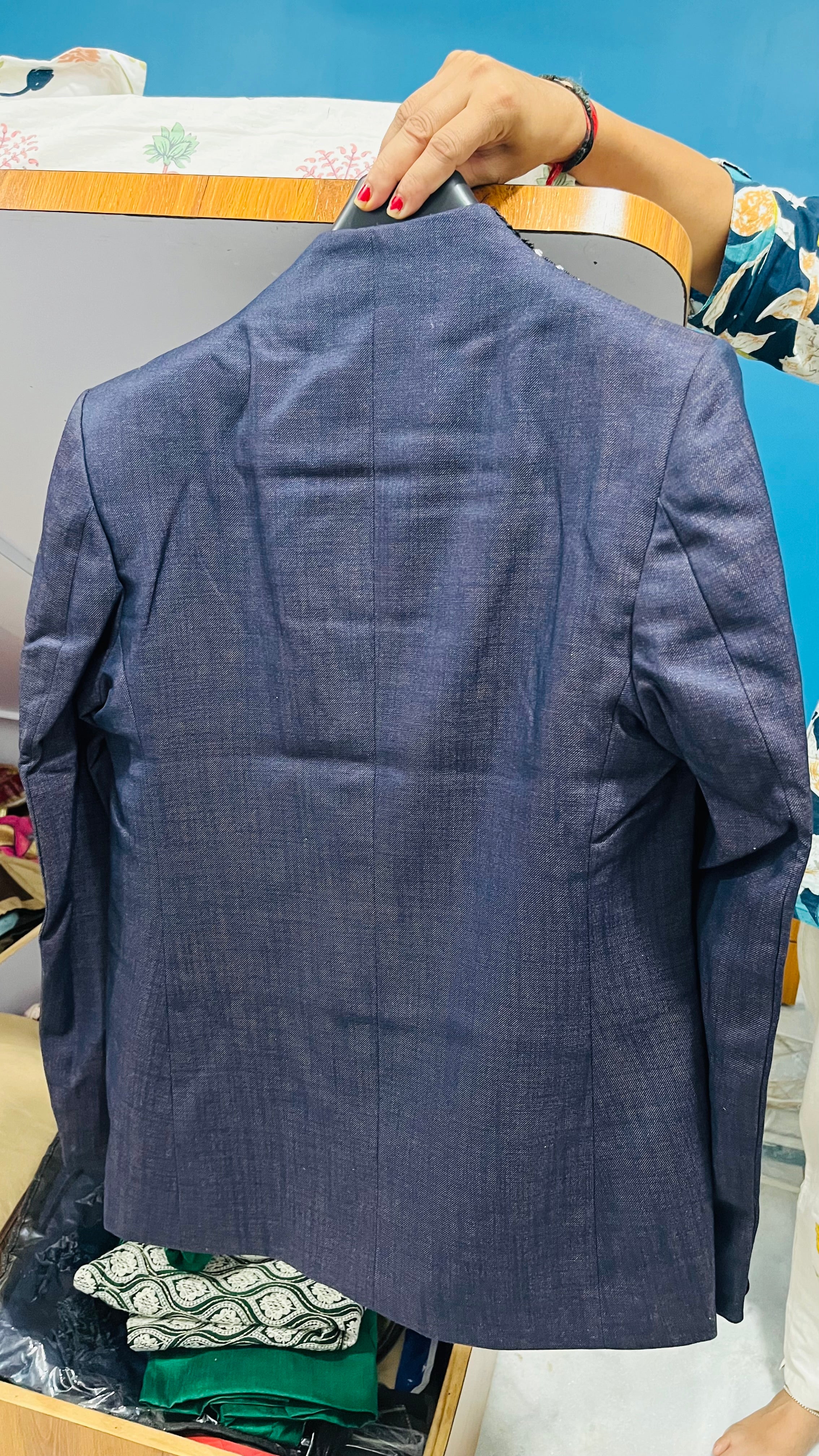 Blue blazer on a hanger against a blue background