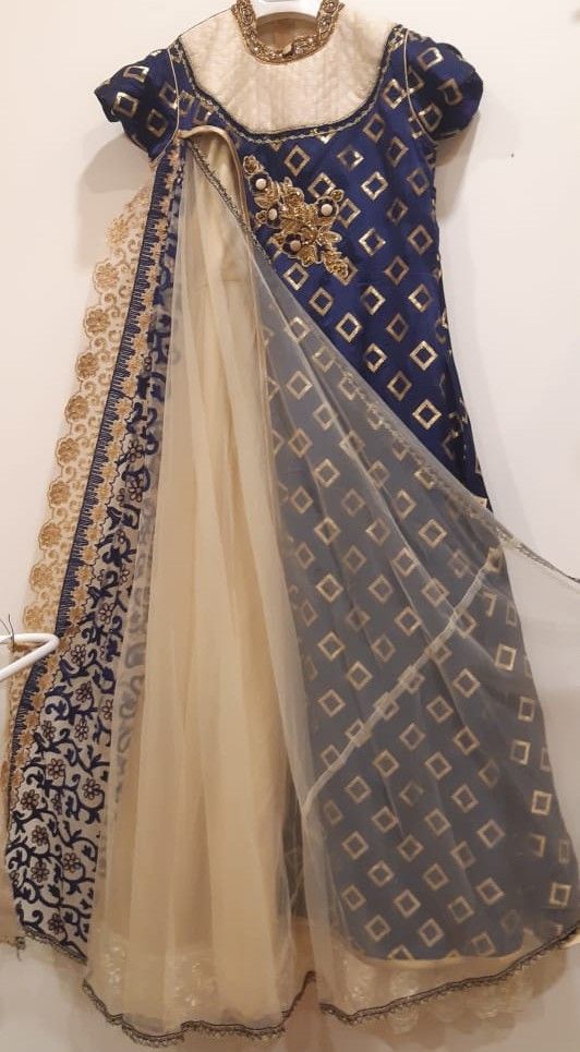 Traditional outfit with blue and gold embroidered top and beige skirt on a white background