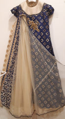 Traditional outfit with blue and gold embroidered top and beige skirt on a white background
