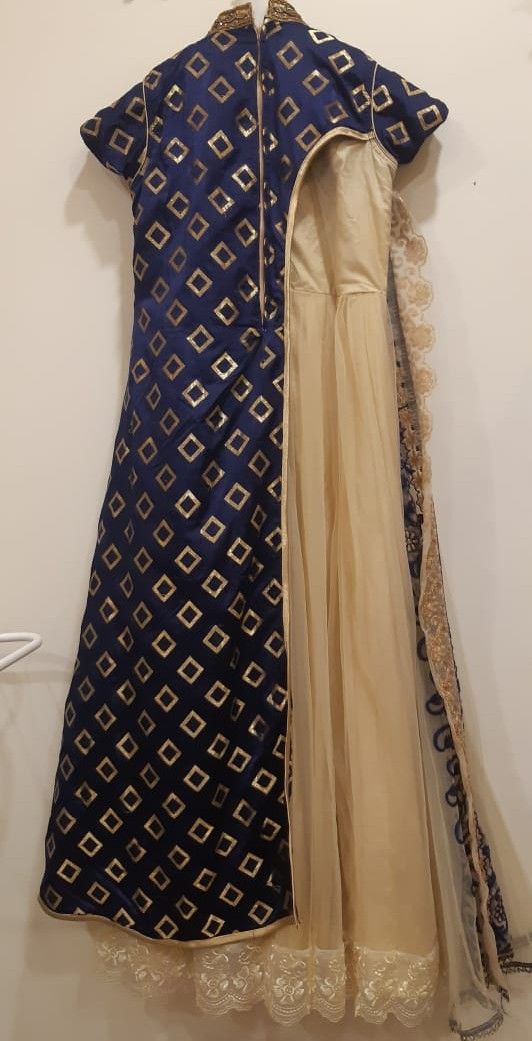Traditional outfit with blue and gold patterned top and beige skirt on a white background