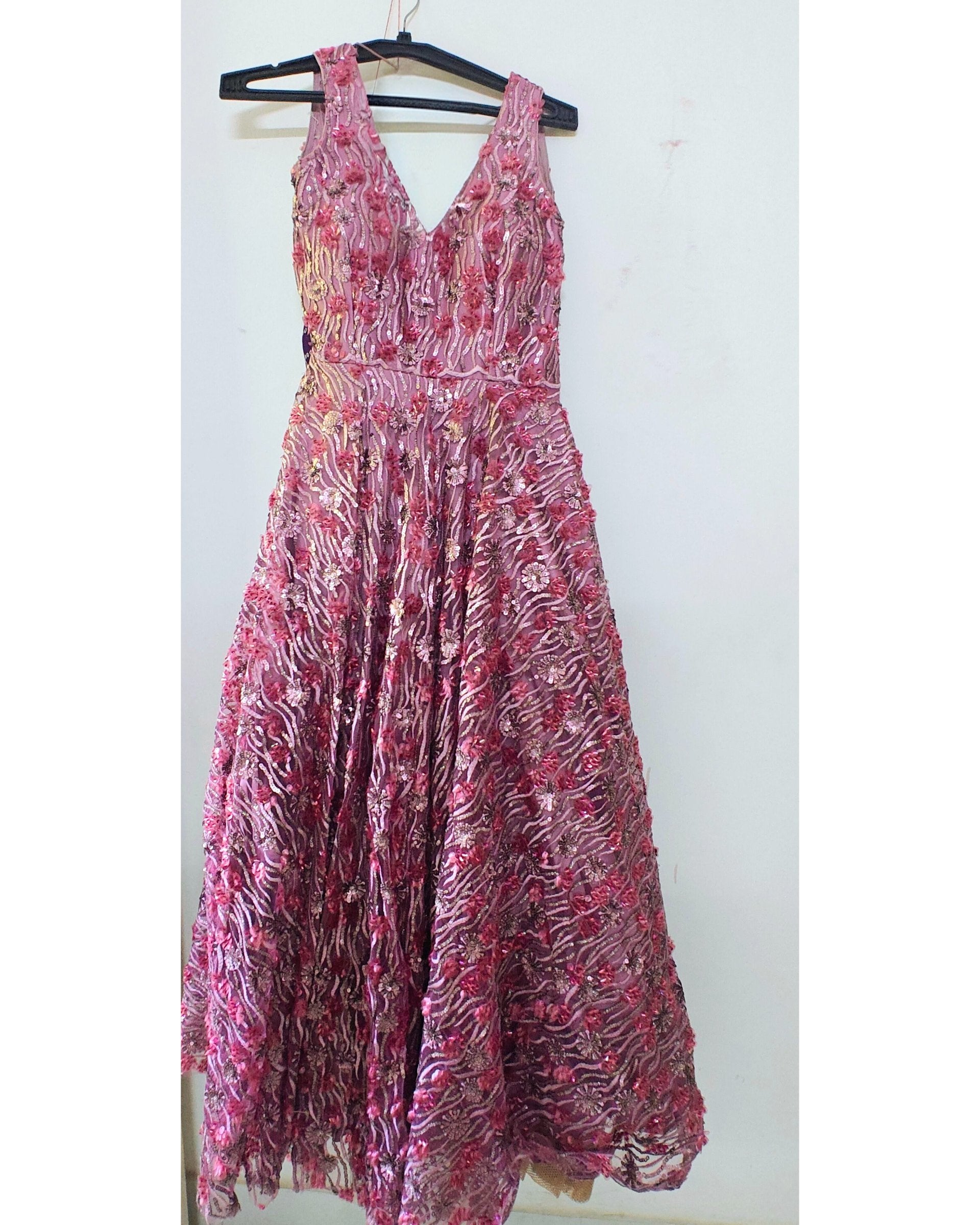 Pink floral dress on a hanger against a white background