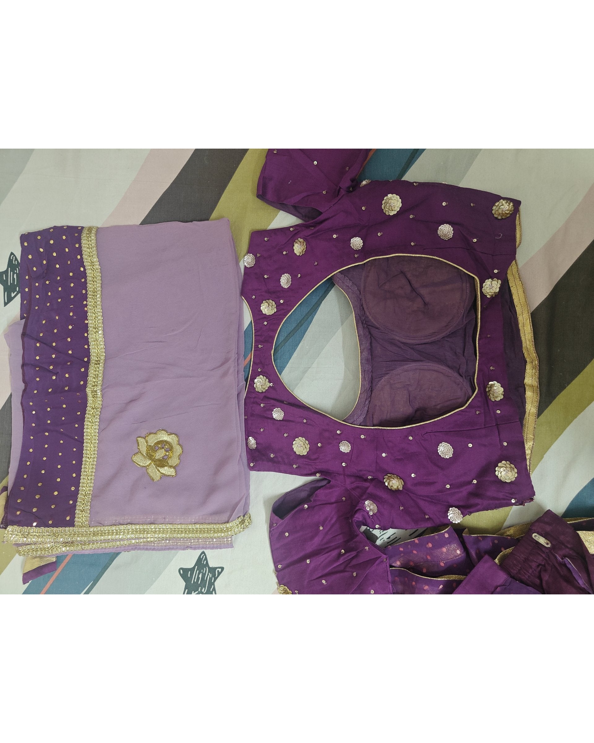 Purple blouse with gold detailing on a colorful fabric background