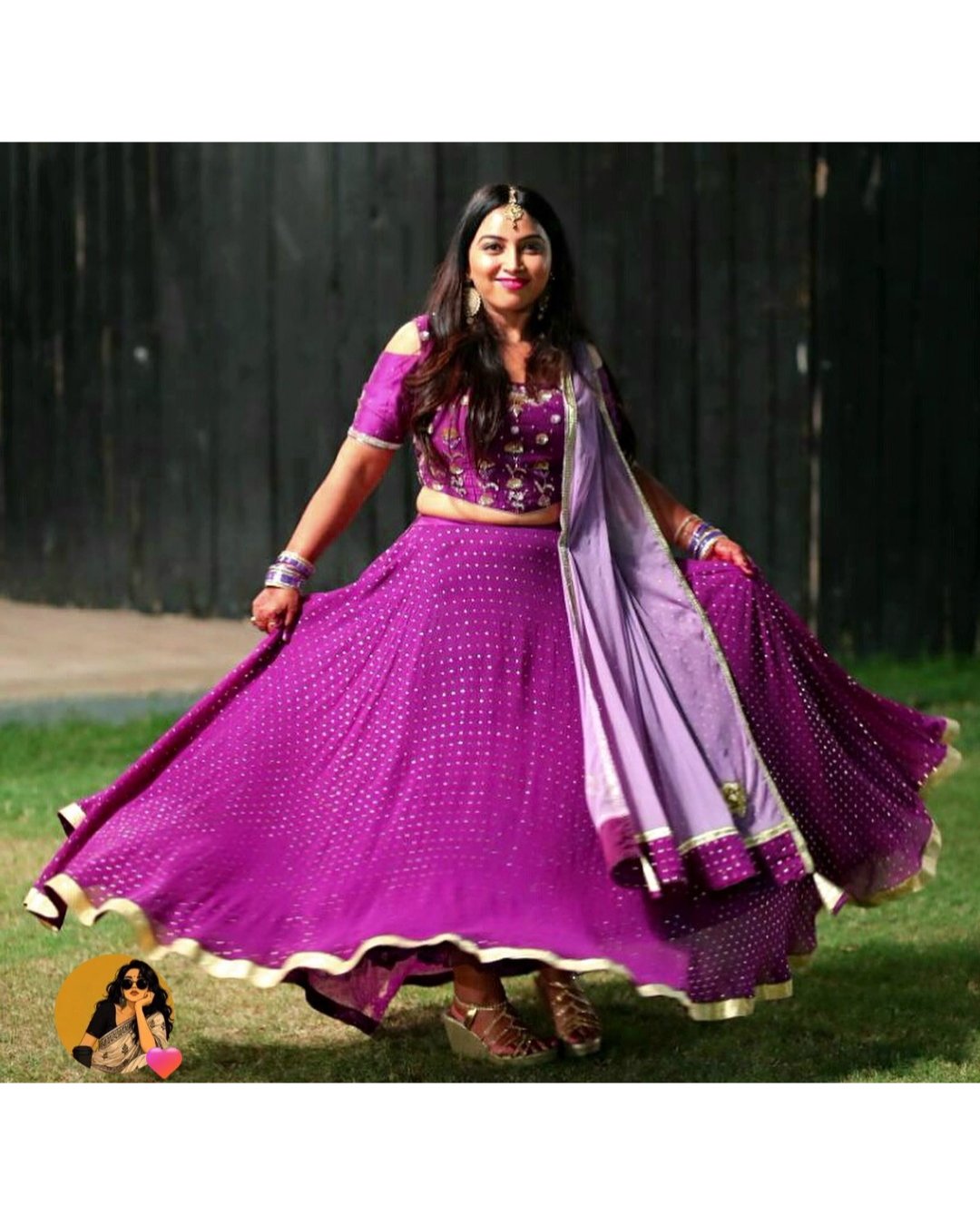 Woman in a purple traditional outfit with a dupatta, standing outdoors.