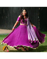 Woman in a purple traditional outfit with a dupatta, standing outdoors.