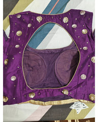 Back view of purple blouse with gold embellishments on a geometric patterned surface