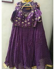 Purple traditional outfit with gold patterns on a hanger against a plain background