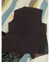 Back view of a very deep plum-colored vest laid flat on a striped bedsheet background.