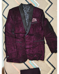 A men's formal blazer in a deep purple brocade pattern with black satin shawl lapels, displayed flat on a patterned beige and blue background.
