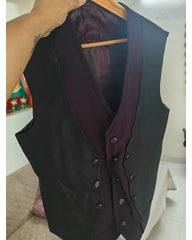 A black double-breasted waistcoat vest with a dark plum lining, hanging on a wooden hanger with a hand holding the collar.