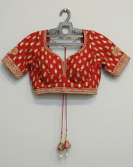 Red and gold embroidered blouse on a hanger against a gray background