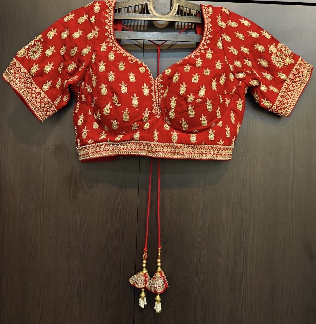 Red blouse with gold patterns hanging on a dark surface