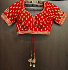 Red blouse with gold patterns hanging on a dark surface