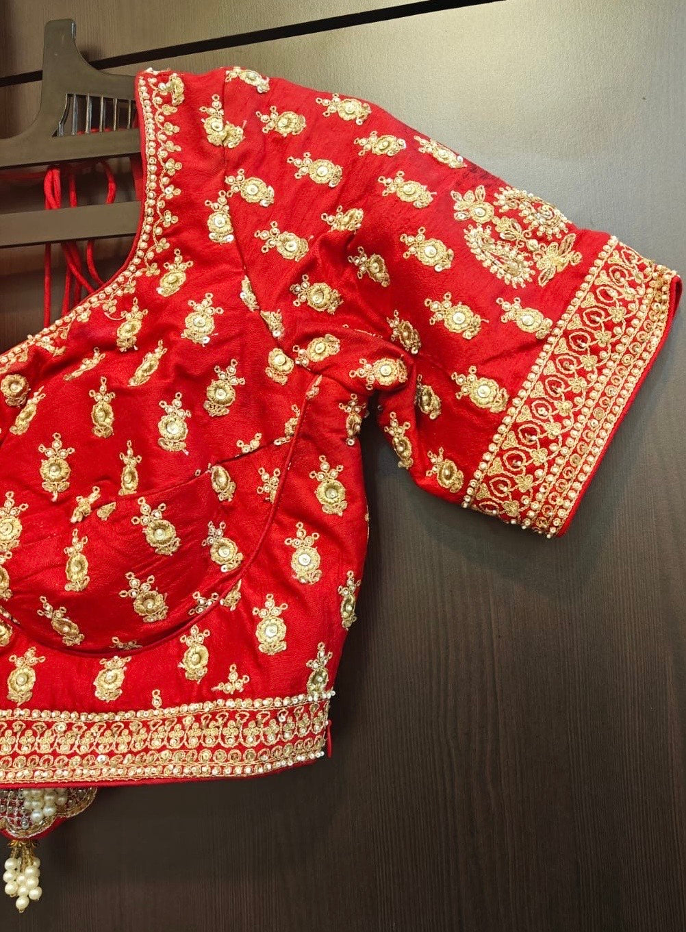 close up view of Red embroidered blouse with gold patterns on a dark background