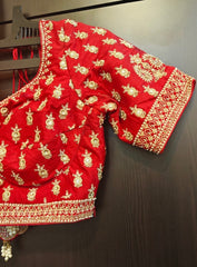 close up view of Red embroidered blouse with gold patterns on a dark background