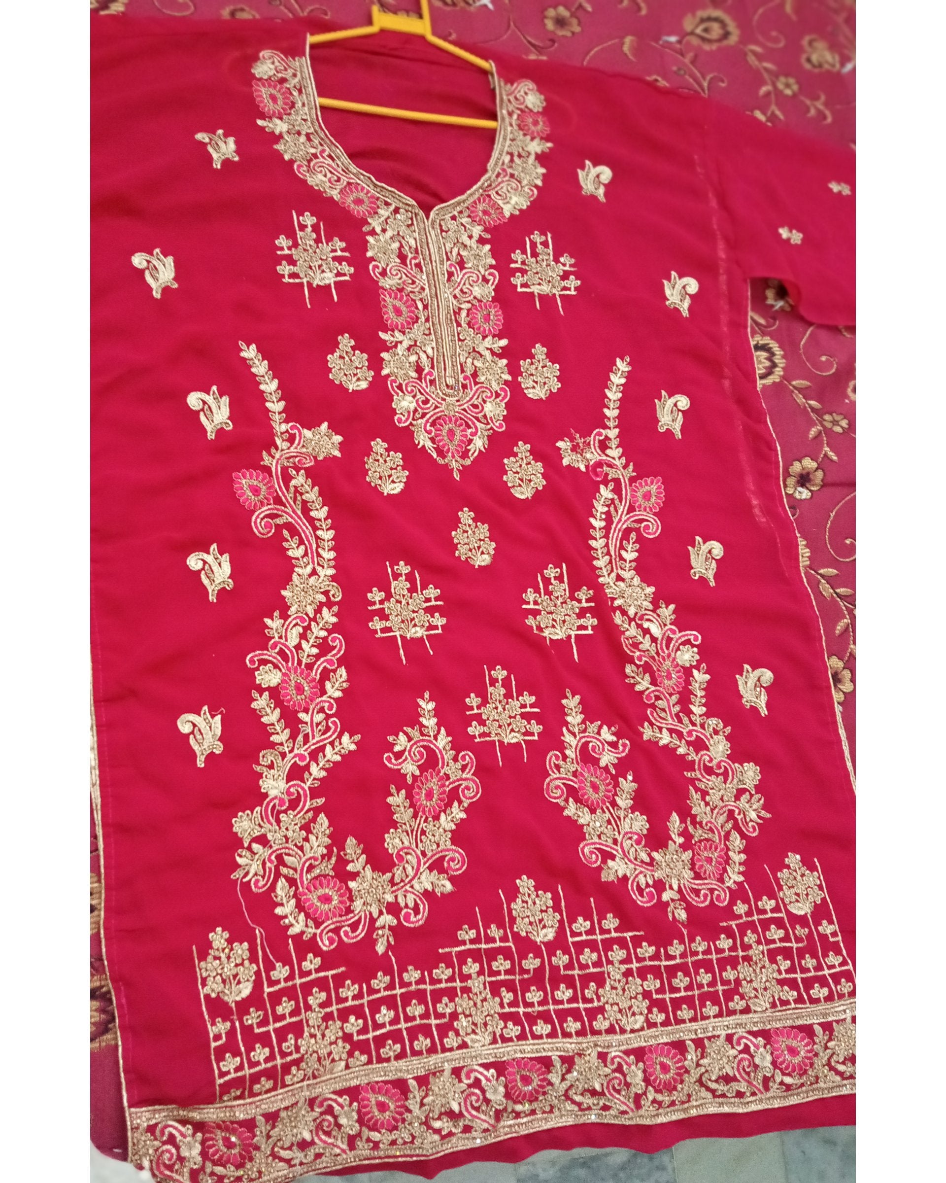 Red embroidered garment on a hanger with a floral pattern